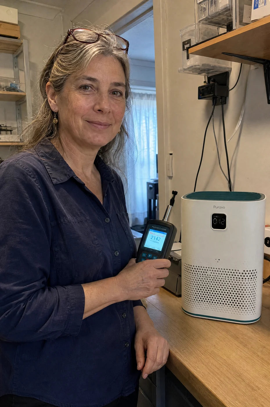 An indoor air quality consultant in her test room holding a particle counter toward Puravo Air