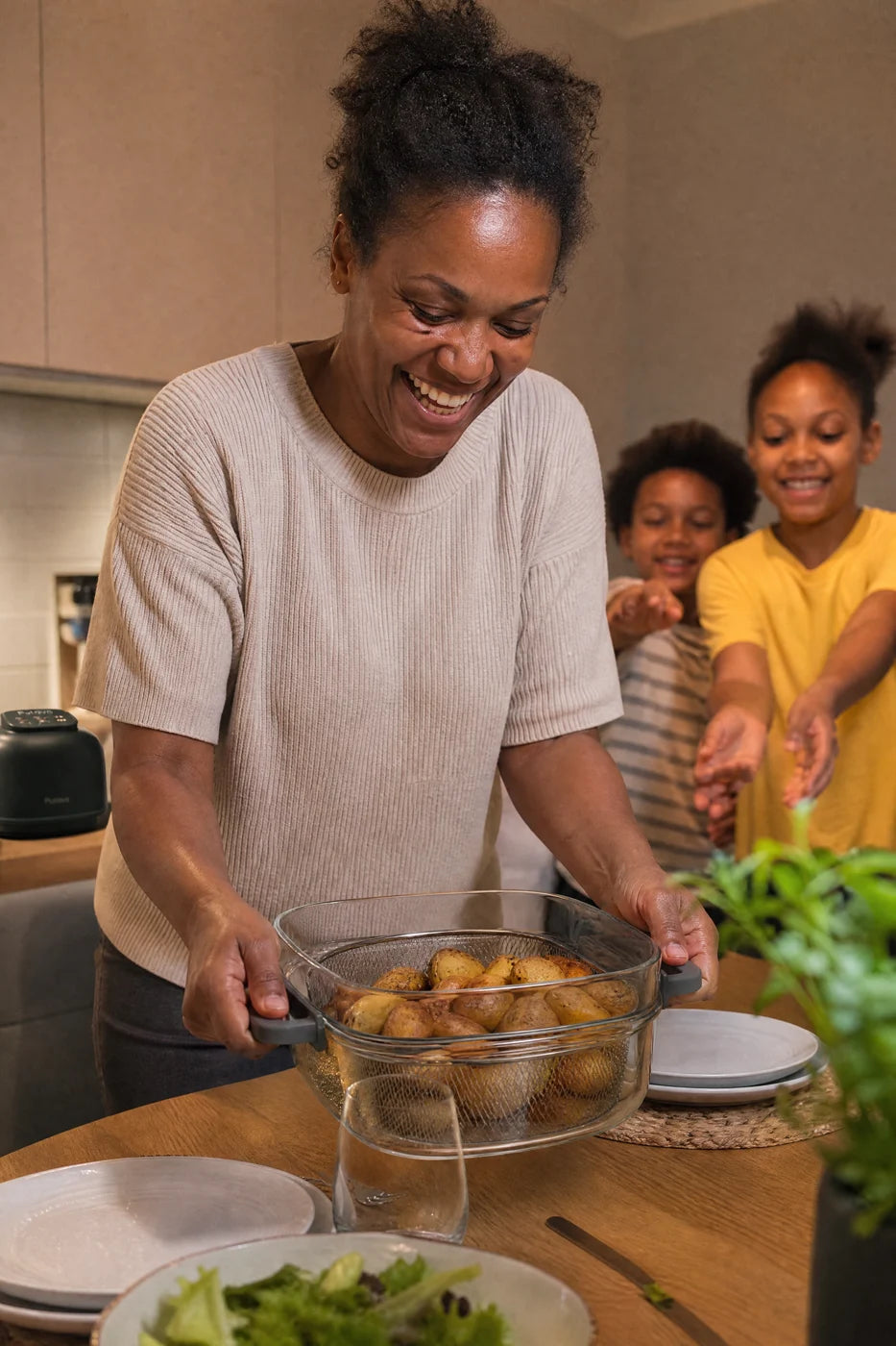A mother carrying the glass bowl of Puravo Glass full of roast potatoes to the family table
